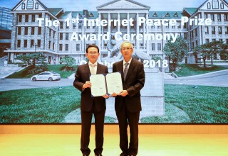 Two men are jointly holding an award certificate.